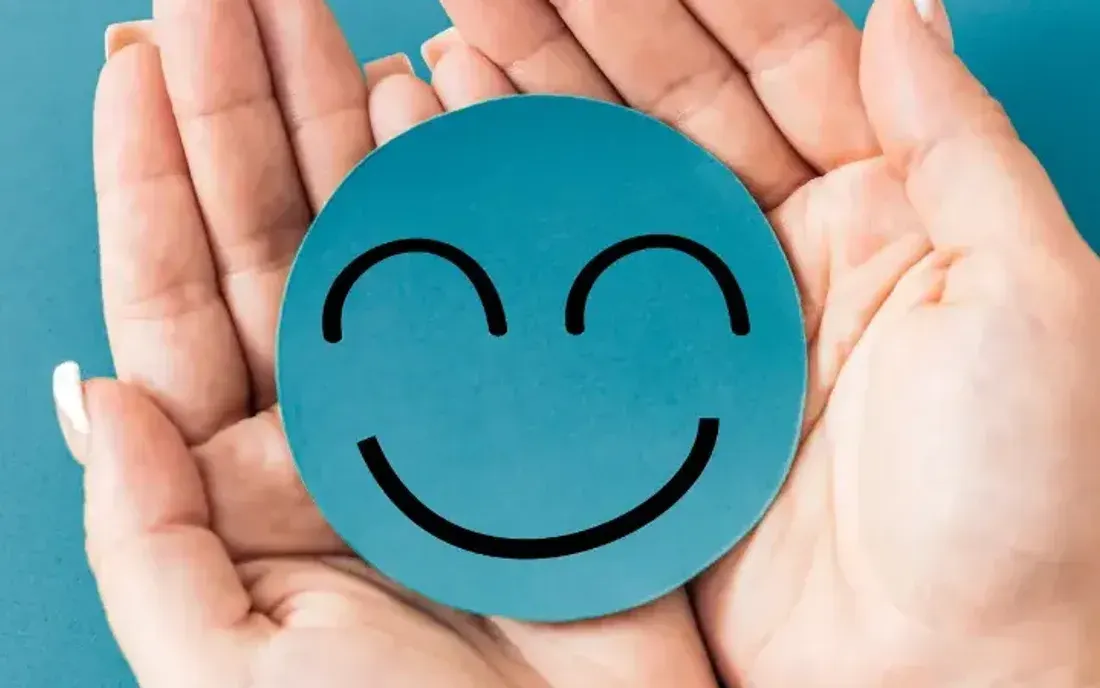 Two hands holding a paper smiley face